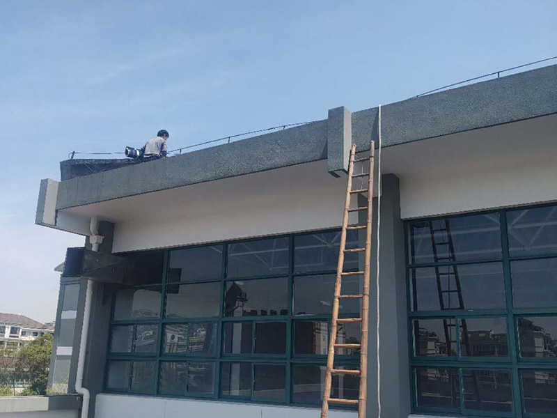 學(xué)校屋頂防水：屋頂做防水前，要先對(duì)需要防水施工的屋頂基層進(jìn)行清潔，因?yàn)楹芏喾浪┕ぶ幸苊庖恍╇s物、塵土等，打掃干凈了更有利于防水施工效果。屋頂防水施工就與室內(nèi)防水施工差不多，室內(nèi)的地漏、水管位置等都要重點(diǎn)涂刷，而屋頂中的水落口、女兒墻、檐口、陰陽角等位置也要先進(jìn)行針對(duì)性的施工，也被稱為附加層施工。屋頂施工防水需要不少材料，特別是防水用的改性瀝青卷材、防水涂料等等，先對(duì)基層鋪貼一層防水卷材，其厚度要符合要求，尺寸根據(jù)屋頂面積進(jìn)行裁剪。卷材一般歐式用熱熔的方式來鋪貼，也就是需要借助火焰噴槍來加熱進(jìn)行滾鋪、粘貼，卷材從檐口處與屋脊平行的方向由下而上進(jìn)行鋪貼。卷材的各個(gè)搭接處都要用噴槍來加熱粘結(jié)牢固，并且在邊緣末端收頭處要用密封膏來嵌填嚴(yán)密好才行。卷材鋪貼好后，要再一次進(jìn)行屋頂清潔，保障干凈、干燥的施工環(huán)境，這時(shí)候就可以進(jìn)行第一層的防水涂料刷涂了，第一遍一定要涂滿，不能出現(xiàn)遺漏、裂紋、氣泡、黏合不牢固等現(xiàn)象。