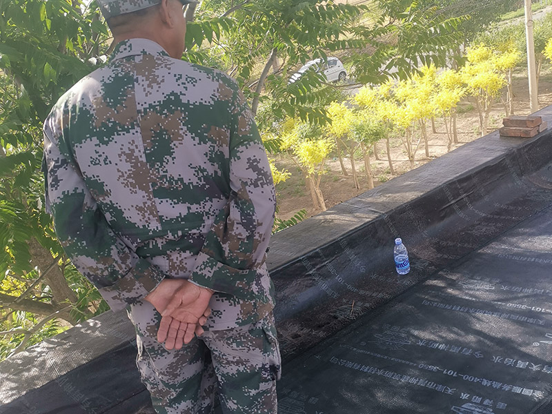 屋頂防水卷材鋪貼:清除基層表面雜物、油污、砂子，凸出表面的石子、砂漿疙瘩等應(yīng)清理干凈，清掃工作必須在施工中隨時(shí)進(jìn)行，并修補(bǔ)平整表面。尤其鏟除排水口、煙囪、管壁上的水泥砂漿等附著物；根據(jù)施工現(xiàn)場(chǎng)狀況，進(jìn)行合理定位，確定卷材鋪貼方向，在基層上彈好卷材控制線，依循流水方向從低往高進(jìn)行卷材試鋪。卷材試鋪后，先將要鋪貼的卷材剪好，反鋪于基面上(即是底部隔離紙朝上)，撕剝?nèi)ゾ聿母綦x紙。撕剝時(shí)，已剝開(kāi)的隔離紙宜與粘結(jié)面保持45～60度的銳角，防止拉斷隔離紙，盡量保持在自然松弛狀態(tài)，但不要有皺折。
