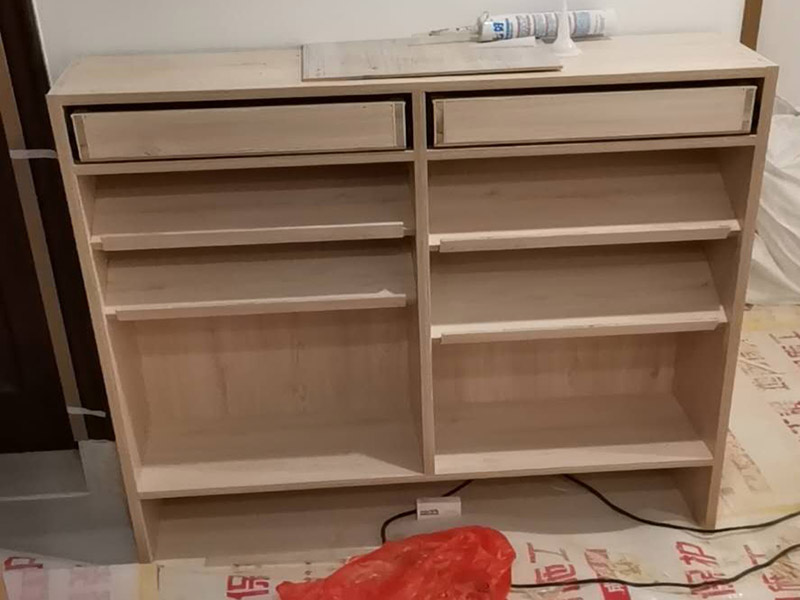 家具柜體安裝：用墊布點好地板，先從靠墻的一端寬du側(cè)板開始組裝，將寬側(cè)板平放于地面上(離后墻面保持700mm間隔)。首先將填好的三合一膠塞的板件，平放在墊布上，檢查孔距與圖紙相符，并裝上三合一單連桿。然后將固層釘上木塞，固定于寬側(cè)板上面，頂板大柄孔朝上，其余固層都朝下，腳線大柄孔朝內(nèi)(中間固層與L架高度一致，即底板到固層內(nèi)空為960mm，現(xiàn)場打?qū)影蹇?。放上側(cè)板，釘上木塞，木塞要求連通兩邊的固層。在第二個柜固層上面裝好雙連桿，留意雙連桿上面大柄只能鎖住一半，即90°。當(dāng)兩件固層與側(cè)板固定后再同時擰緊大柄。 釘背板：把裝好的整體柜側(cè)放在點好墊布的地板上面，墊平側(cè)板成統(tǒng)一平面。用拉尺量好柜子的對角尺寸，調(diào)至相等，從寬測板處開始裝第一塊背板，留意假如中間有固層釘釘子時，先用鉛筆畫好固層的中央線，再釘釘子。